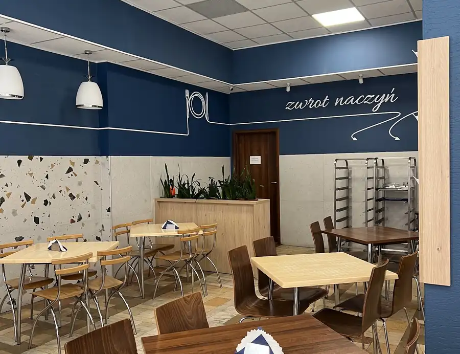 Sala z granatowymi kolumnami i drewnianymi stolikami